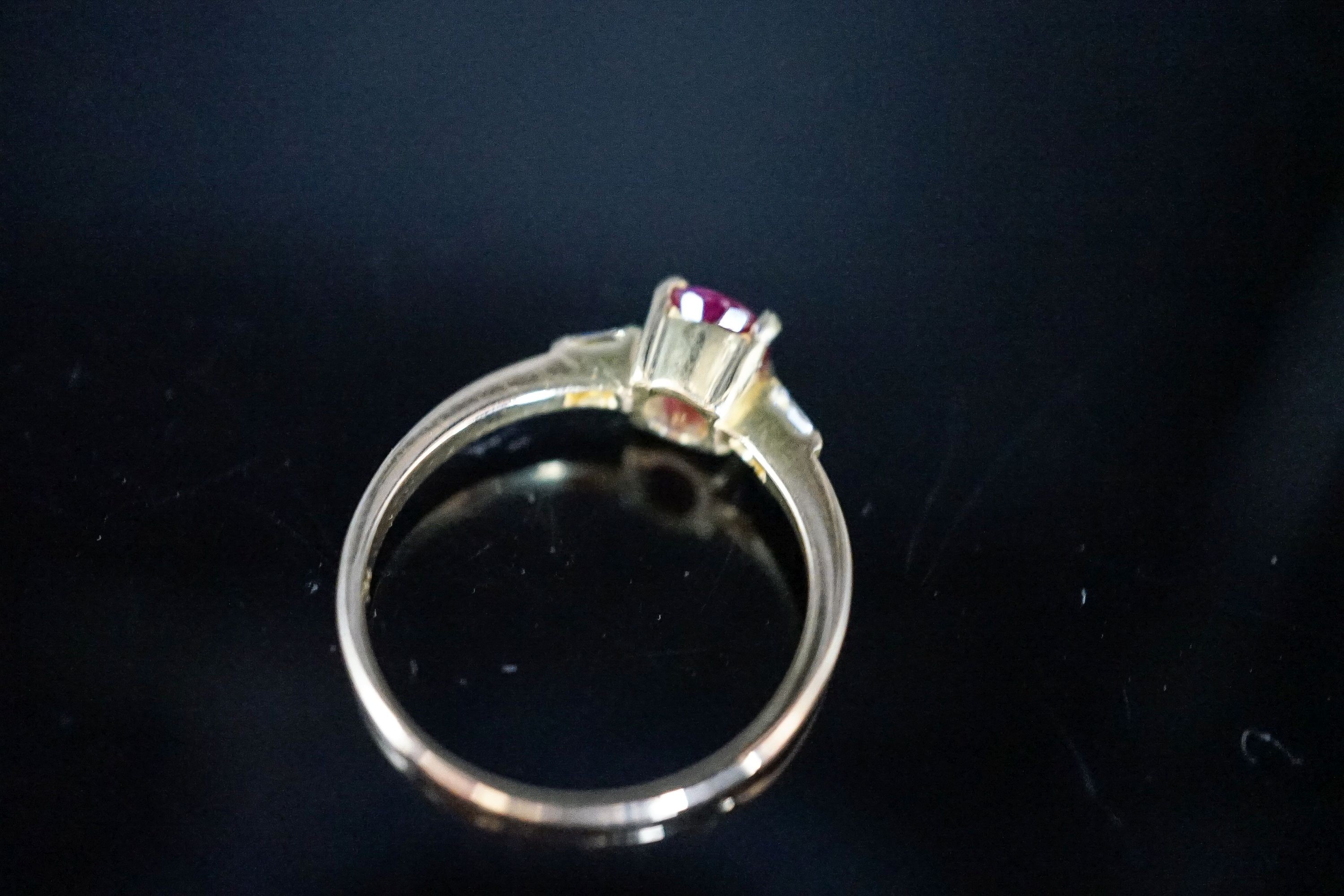 A modern 18ct gold and single stone oval cut ruby ring, with diamond set shoulders, size O, gross weight 2.7 grams.